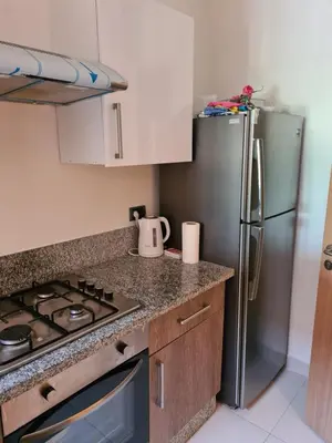 a kitchen with a stainless steel refrigerator and a stove at Appartement chic avec jardin a Prestigia Golf City in Marrakech