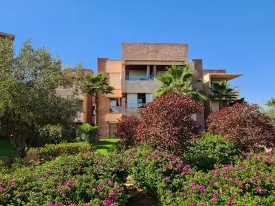 an apartment building with flowers in front of it at Appartement chic avec jardin a Prestigia Golf City in Marrakech