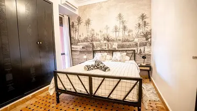 a bedroom with a bed with a painting on the wall at Appartement aux portes de la palmeraie in Marrakech