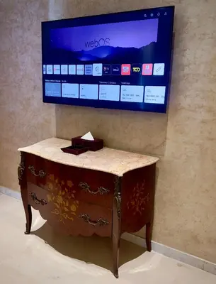 a tv hanging on a wall with a wooden table at Sillage Palace Sky & Spa in Marrakech