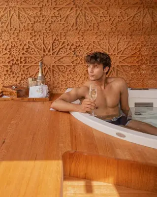a man sitting in a bath tub with a glass of wine at Riad la clé d'or & spa in Marrakech