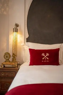a bed with a red pillow with a cross on it at Riad la clé d'or & spa in Marrakech