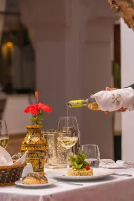 a person pouring a glass of wine on a table at Riad la clé d'or & spa in Marrakech