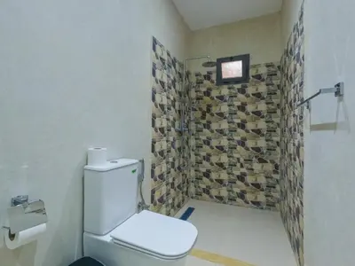 a bathroom with a toilet and a tiled wall at RIAD REDWAN in Marrakech