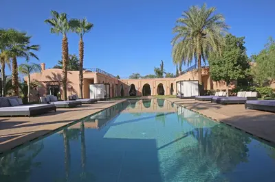 a swimming pool with palm trees and a building at Domaine DAR JMEL & Dar Abi Samama in Marrakech
