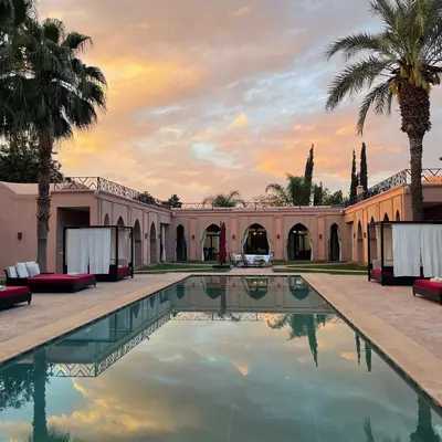 an outdoor pool with palm trees and a building at Domaine DAR JMEL & Dar Abi Samama in Marrakech