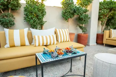 a couch on a patio with a tray of food on a table at Riad Les Yeux Bleus in Marrakech