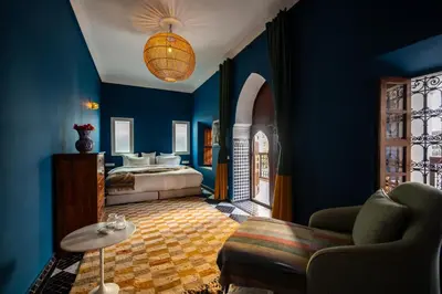 a bedroom with blue walls and a bed and a couch at Riad Les Yeux Bleus in Marrakech