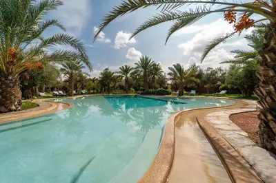 a swimming pool with palm trees in a resort at Domaine Alma Marrakech in Marrakech