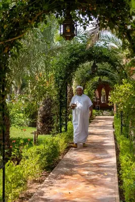 a man walking down a path in a garden at Domaine Alma Marrakech in Marrakech
