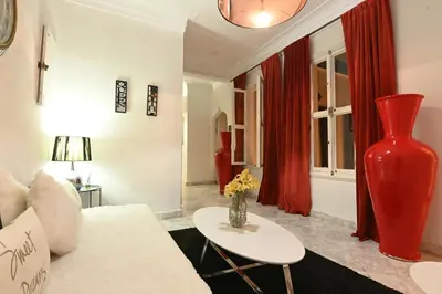 a living room with a white couch and a red vase at Riad 5 Chambres & Piscine & Breakfast - Marrakech in Marrakech