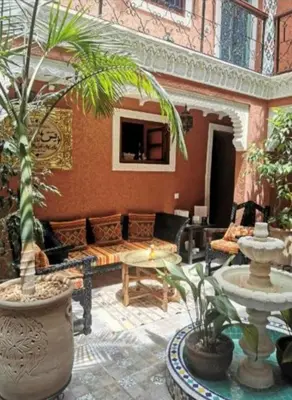 a patio with a couch and a table and some plants at Dar Al Hayat in Marrakech