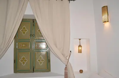 a green door in a white room with curtains at Riad Dar Hamid Hotel & Spa in Marrakech