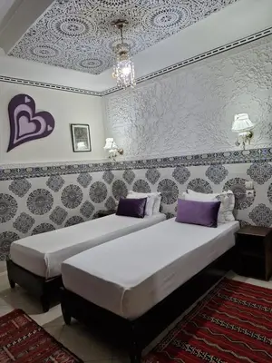 a bedroom with two beds with purple pillows at Riad De La Semaine in Marrakech