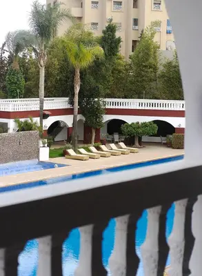 a bridge over a pool with palm trees and a building at Targafit Hotel & Hammam in Marrakech