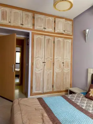 a bedroom with wooden cabinets and a bed at Firdaouss apartment in Marrakech