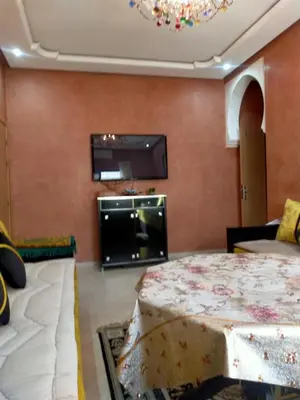 a living room with a bed and a flat screen tv at Firdaouss apartment in Marrakech