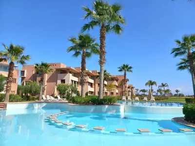 a swimming pool with palm trees in a resort at Prestigia Appartement de luxe in Marrakech