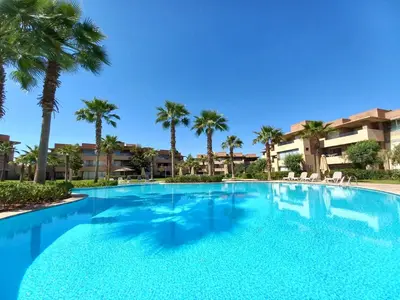 a large swimming pool with palm trees in a resort at Prestigia Appartement de luxe in Marrakech