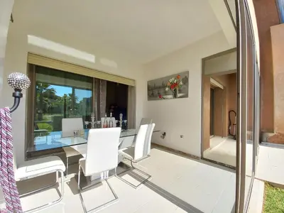 a dining room with a glass table and white chairs at Prestigia Appartement de luxe in Marrakech