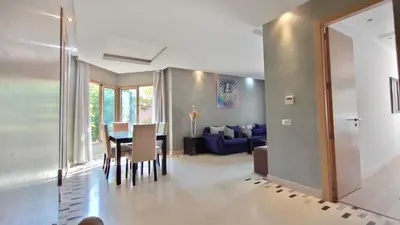 a dining room and living room with a table and chairs at Prestigia Appartement de luxe in Marrakech