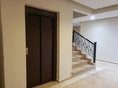 a hallway with a black door and stairs at Central Aparts Av Prince Moulay Abdellah in Marrakech