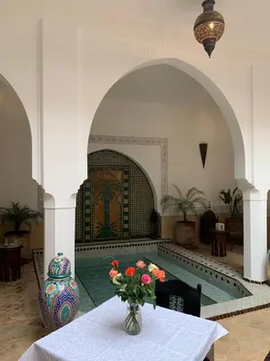a room with a pool and a table with a vase of flowers at Riad Dar Talah in Marrakech