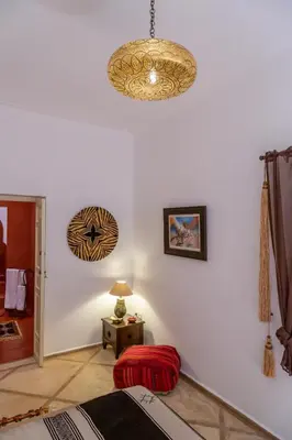a room with a white wall with a chandelier at Riad Dar Talah in Marrakech