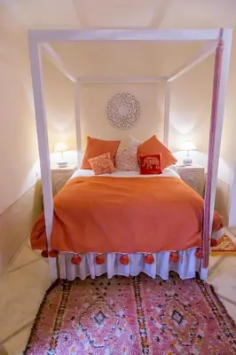 a bedroom with a bed with an orange comforter at Riad Dar Talah in Marrakech
