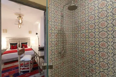 a bedroom with a bed and a shower with a glass door at Riad-Shakho-Marrakech in Marrakech