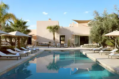 a pool with chairs and umbrellas next to a building at Villa Dar Challa in Marrakech