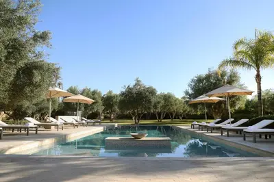 a swimming pool with lounge chairs and umbrellas at Villa Dar Challa in Marrakech