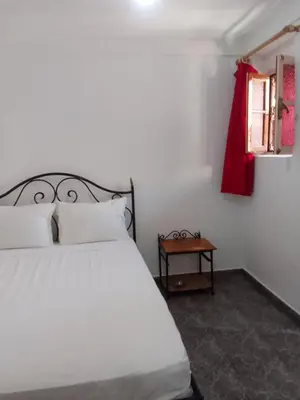 a bedroom with a white bed and a red curtain at Hotel imouzzer in Marrakech