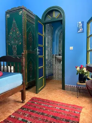 a bedroom with a green door and a red rug at Casa del Sol Marrakech in Marrakech