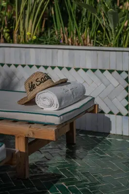 a bench with a towel and a hat on it at Riad Le Saadien ,Adult only in Marrakech