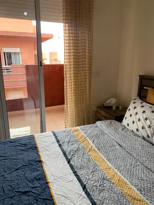 a bedroom with a bed and a sliding glass door at Appartement zen in Marrakech