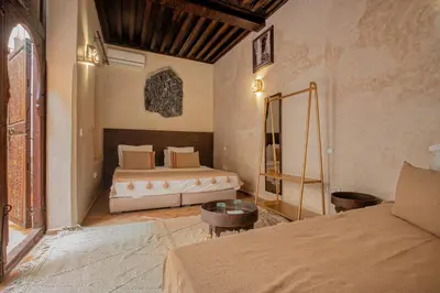 a bedroom with two beds and a table in it at Riad Tassili Marrakech in Marrakech