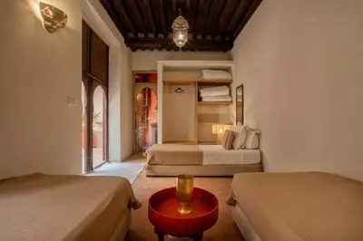 a bedroom with two beds and a red table at Riad Tassili Marrakech in Marrakech