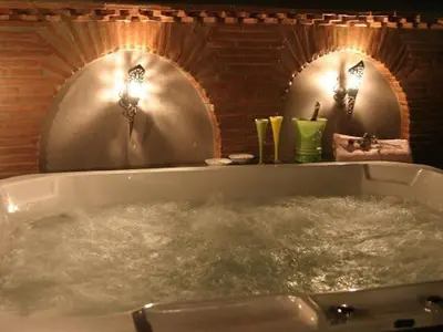 a bath tub filled with water in front of two mirrors at Riad Carllian in Marrakech