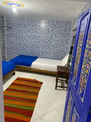 a bedroom with a bed and a blue door and a rug at Hostel Essassi 23 in Marrakech