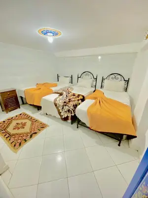 two beds in a room with white tile floors at Hostel Essassi 23 in Marrakech