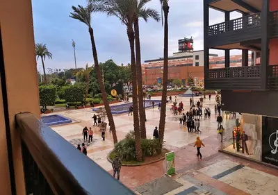 a group of people walking around a plaza with palm trees at Appartement Haut Standing Gueliz Plaza avec Vue in Marrakech
