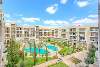 an apartment complex with a swimming pool and palm trees at Royal Deluxe Gold - Marrakech, Luxe Pool View in Marrakech