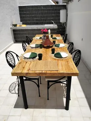 a long wooden table with chairs and plates on it at Riad Siena II in Marrakech
