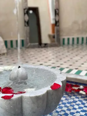 a water fountain in a building with red flowers at L'Emeraude de la Médina in Marrakech