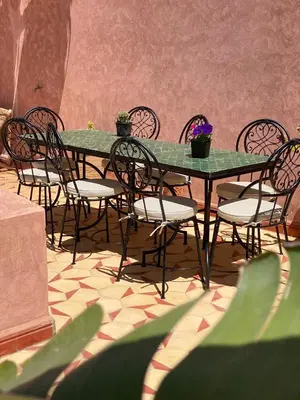 a green table and chairs with plants on a patio at L'Emeraude de la Médina in Marrakech