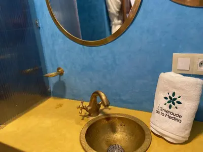 a sink in a bathroom with a mirror and a towel at L'Emeraude de la Médina in Marrakech