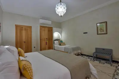 a bedroom with two beds and a chandelier at Riad Banatti in Marrakech