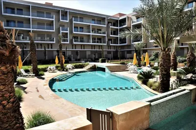 an apartment building with a swimming pool and palm trees at Royal Deluxe Silver - Marrakech, Luxe Pool View in Marrakech