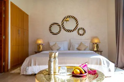 a bedroom with a white bed with a table and two mirrors at Riad villa saphir & SPA in Marrakech